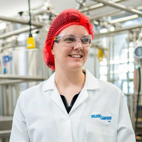 Lauren-Zellner-standing-in-front-of-equipment-smiling-off-camera