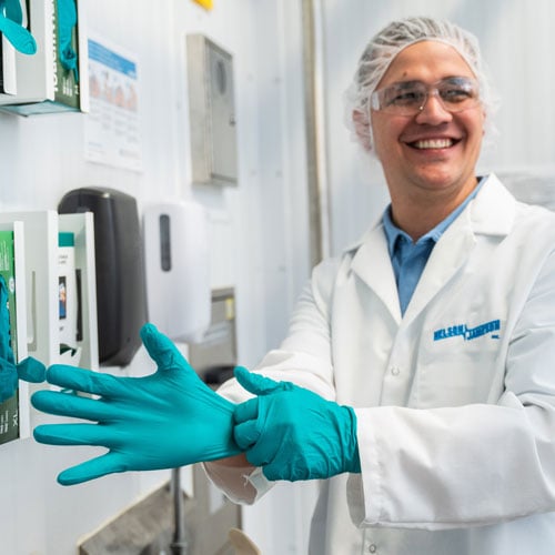 Adam-Monson-putting-on-a-pair-of-gloves-smiling-off-screen-2